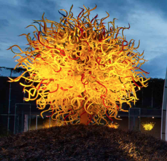Large illuminated yellow, orange, and red glass sculpture comprised of hundreds of blown glass tendrils