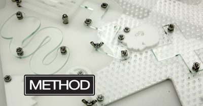 Transparent, textured plastic shapes adhered to a white surface with nuts and bolts. Black and white text in lower left corner reads "METHOD"