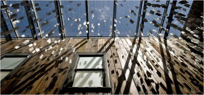 Art installation viewed from below, featuring hundreds of white pieces of paper tied to string, suspended from the windowed ceiling.