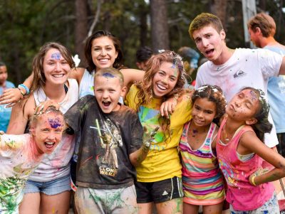 Group of college-aged camp counselors and children after a paint ball fight.