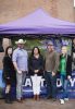 Group of people stand smiling in front of a banner under a purple tent, the banner reading "#sustainable UW"