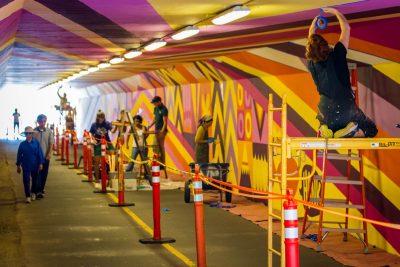 Group of artists paint an underground pedestrian underpass with a brightly colored abstract mural