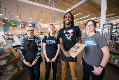 Group of employees stand in an art supply store smiling,