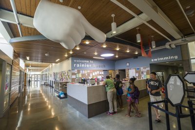 Interior of a community center lobby. A family checks in at the front counter.