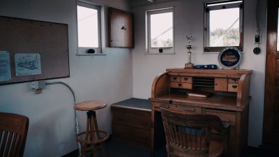 Small work space with several windows and a vintage rolltop desk and chair