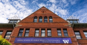 Red bricked, windowed university building with a purple banner in front reading "Evans School of Public Policy & Governance"