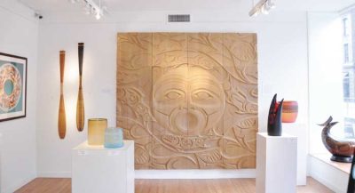 Brightly lit white walled gallery space featuring 3D and 3D indigenous artwork.