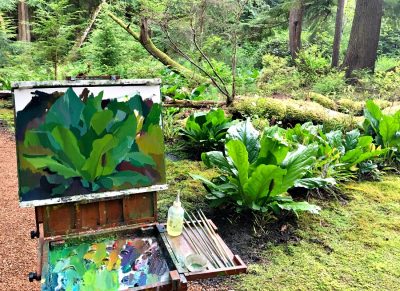 Artist's easel and paint set, with a painting of bright green foliage in a forested setting.