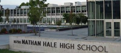 Exterior view of a modern high school campus, a sign reading "Nathan Hale High School" in front