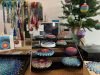 Tabletop display of colorful art for sale - some beaded jewelry works alongside painted Christmas ornaments and oval sculptures.