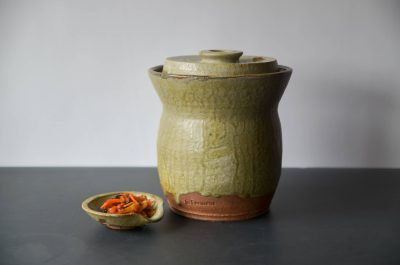 Handmade light green ceramic fermenting jar.