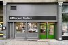 Exterior of an art gallery storefront with green double doors. Text over the windows and doors reads "J. Rhinehart Gallery"