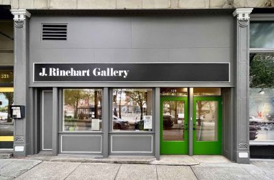 Exterior of an art gallery storefront with green double doors. Text over the windows and doors reads "J. Rhinehart Gallery"