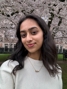 Photo of Maryam in front of cherry trees with blossoms