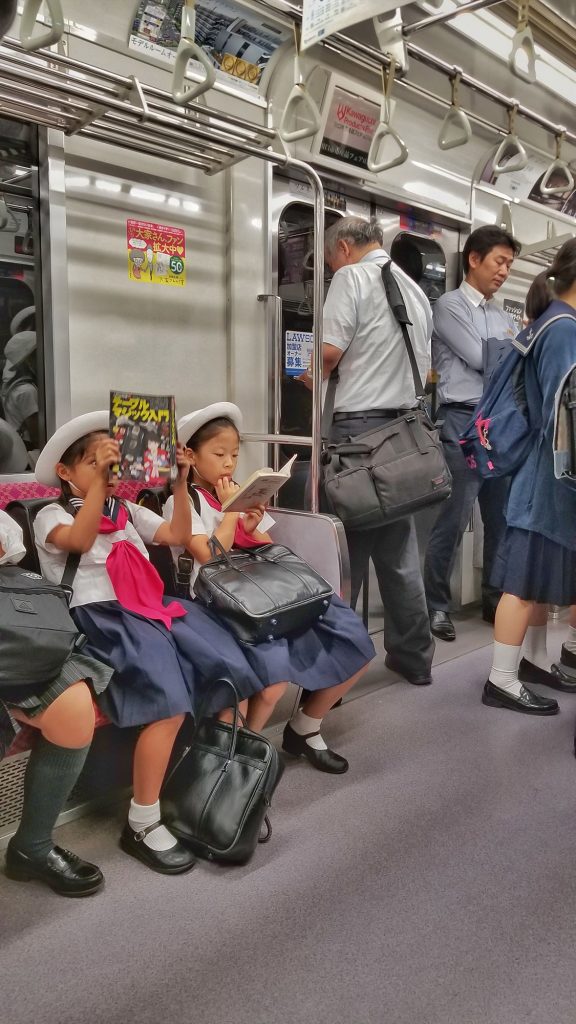 Schoolgirls reading comics on the subway