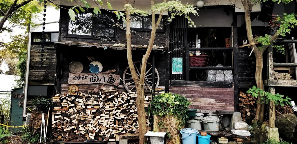 The exterior of a Japanese building with wood stacked out front