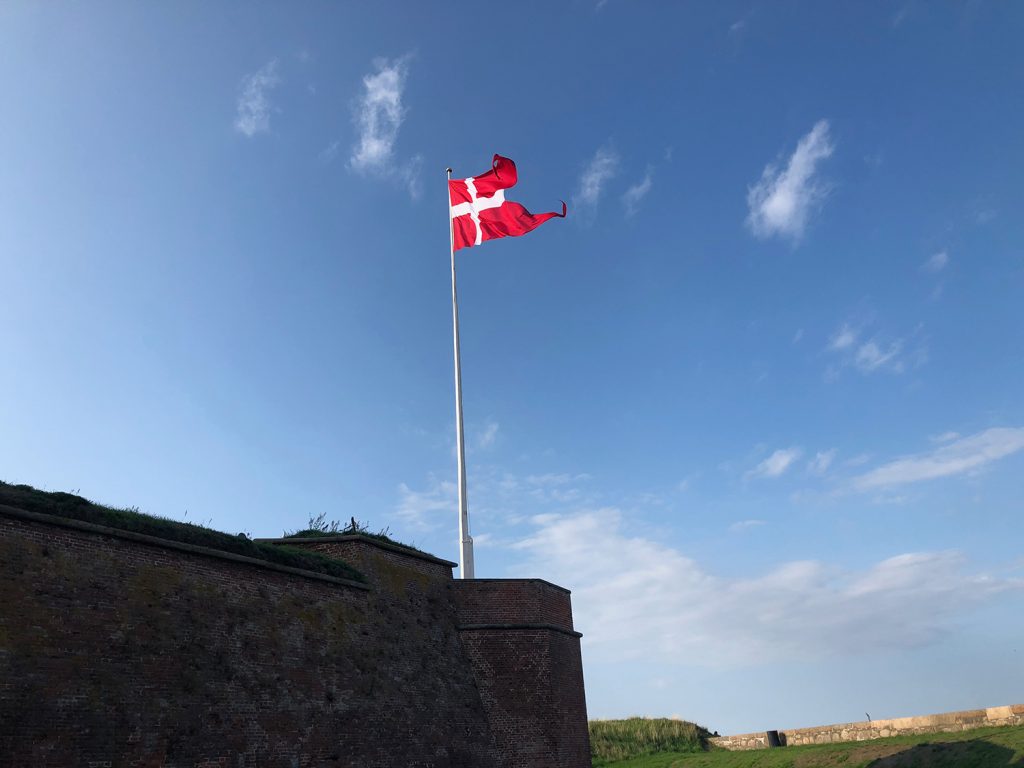A photo of a Danish flag flying against a blue sky