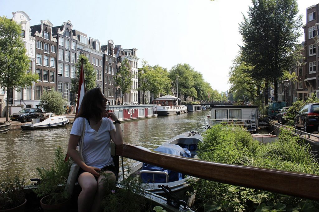 A picture of a woman, almost in silhouette, in front of a canal in Europe