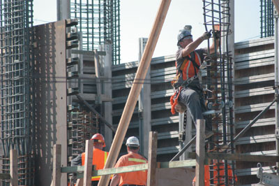 At the construction site, an iron worker prepares rebar for concrete forms.