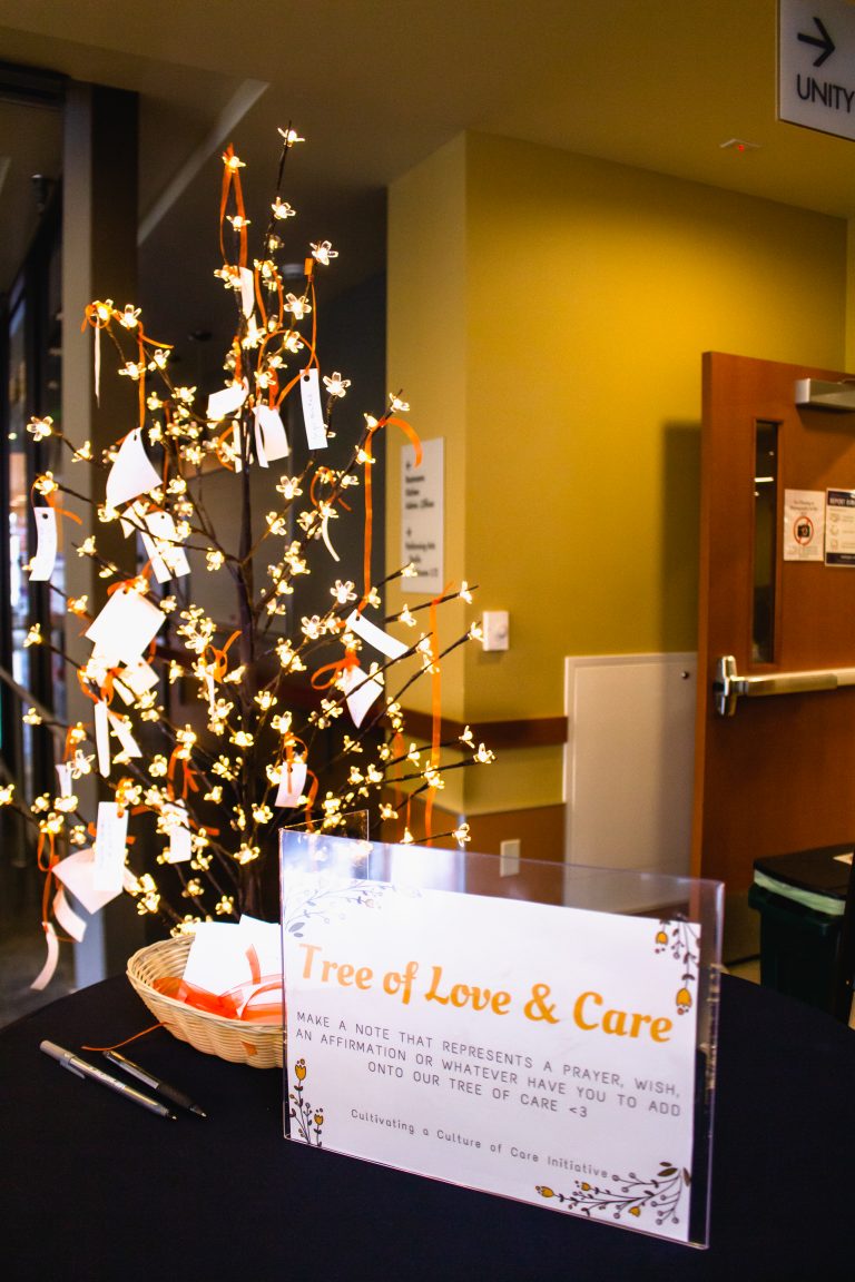 Sign displaying Tree of Love & Care, with tree behind the sign