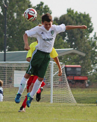 A young soccer player jumps into the air to head the soccer ball during a match.