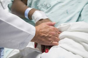 A doctor holds the hands of a burn patient with a bandaged wrist at Harborview Medical Center.