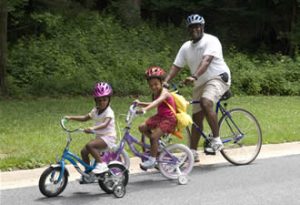 Family with young children riding bikes on road with helmets
