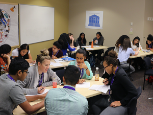 INSIGHT interns work in groups at tables, discussing an epidemiology exercise.