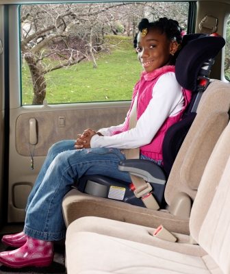 Booster Seat A girl seated in a booster seat with seat belt fastened.
