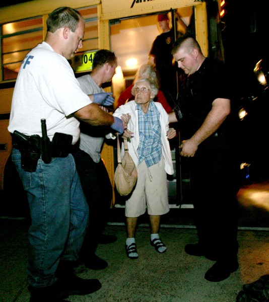 Photo of a sheriff's officer from helps a woman exit a bus at a shelter after Hurricane Gustav.