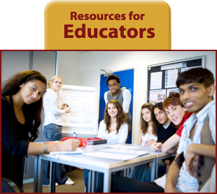 Six students sitting at table and two standing at classroom door all look directly at camera.