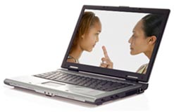 Mother and daughter appear on computer monitor looking at one another face to face; mother is pointing her finger at the daughter as she talks to her.