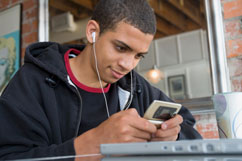 Boy is sitting in front of laptop with headphone and I-Pod.