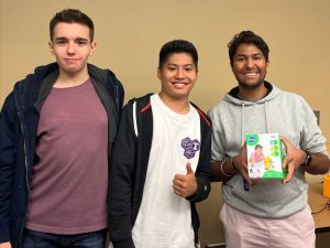 Three guys holding an adapted toy