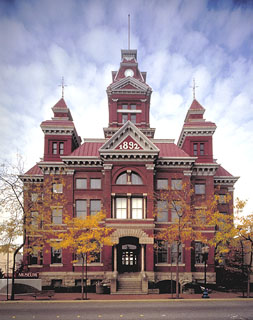 Old red bricked, multi-story city hall building. Large white text on the top facade reads "1892".