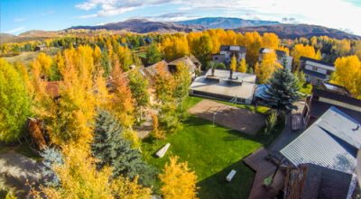 Aerial view of an art center campus, surrounded by golden aspen trees and mountains.