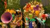 Group of people dressed in handmade bug costumes operating a float covered in large flower sculptures.