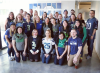 Company photo of a group of smiling people in a lobby, all wearing Seahawks fan shirts and gear.