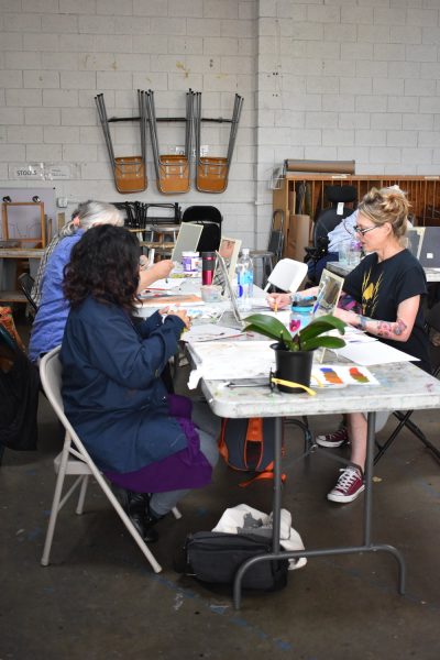 Adults paint at a table in an art studio