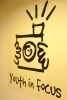 Bold marker drawing on a wall depicting hands holding a film camera, text below reading "youth in focus"