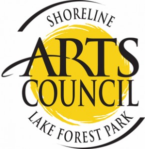 Black text logo reads "Arts Council" over a painterly yellow circle. Black text above read "Shoreline" and black text below reads "Lake Forest Park."