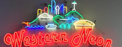 Bright neon sign with a depiction of the Seattle skyline, and neon lettering reading "Western Neon"
