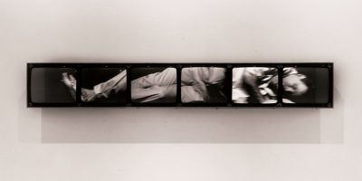 Photo-based art piece installed on a white wall. Artwork consists of mounted and enlarged black and white photographs of a figure.
