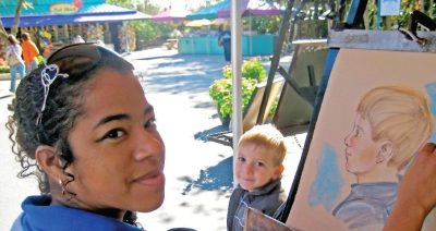 Person draws a portrait of a young smiling child, a Zoo gift shop in the background.
