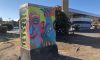 Painted utility box, a gas station visible in the background.