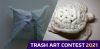 Outline of a sculpted face behind a compostable bag in the shape of a pillow. To the right is a sculpture of a sea turtle made out of packing peanuts. White & gold text in a purple text box below reads "Trash Art Contest 2021"