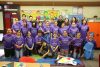 Group of school children and young adult mentors stand in a class room setting, all wearing matching purple tshirts that read "University of Washington; 2017 Alternative Spring Break; The Pipeline Project."