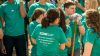 Group of students wearing matching green shirts in a work setting, one holding a shovel. Figure in the foreground is facing away from the camera, and their shirt reads "Impact; Spring Break 2017; 'It is not enough to be compassionate. You must act.' - Dalai Lama."