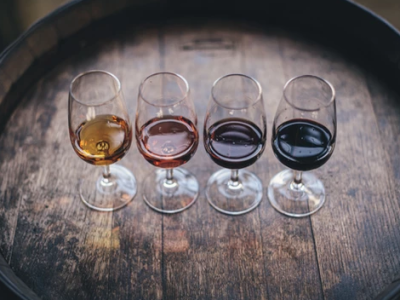 Above view of four wine glasses with different types of wine, sitting on the top of a dark wood barrel.