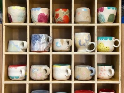 Handmade ceramics mugs in a grid-like shelf, with each mug in its own individual cubby